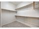 Empty walk-in closet with rods for hanging clothes and neutral carpet flooring at 20160 N Riverbank Rd, Maricopa, AZ 85138