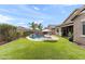 Spacious backyard with lush green grass, beautiful pool with waterfall, and a covered patio for outdoor relaxation and entertainment at 20563 E Carriage Way, Queen Creek, AZ 85142