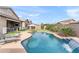 Resort-style backyard features a sparkling pool with a waterfall, an umbrella, lush landscaping, and comfortable lounge chairs at 20563 E Carriage Way, Queen Creek, AZ 85142