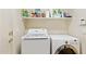 Functional laundry room featuring a modern washing machine, dryer, and ample storage shelf space at 21019 N Sansom Dr, Maricopa, AZ 85138
