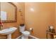 Stylish half-bathroom with a pedestal sink, toilet, and elegant wall decor at 2222 W Morse Ct, Anthem, AZ 85086