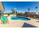 Backyard pool with stone patio, rock features, and seating surrounded by palms and lush landscaping at 2259 E Ivy St, Mesa, AZ 85213