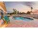 Backyard pool with surrounding stone patio, rock features, and seating at dusk at 2259 E Ivy St, Mesa, AZ 85213