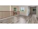 Bright hallway featuring wood-look floors, a wooden railing, and natural light from multiple windows at 3133 N Medallion Ct, Casa Grande, AZ 85122