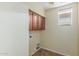 Neutral laundry room features wooden cabinets above hookups and a window providing natural light at 3133 N Medallion Ct, Casa Grande, AZ 85122