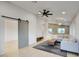 Bright living room showcasing a modern ceiling fan, gray sectional, and a sliding barn door at 3604 W Calle Lejos --, Glendale, AZ 85310