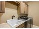 Bright laundry room with tan walls, cream cabinets, utility sink and stainless steel washer and dryer at 37440 N 104Th Pl, Scottsdale, AZ 85262