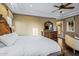 Bright main bedroom features tray ceilings, a ceiling fan, wood floors, and a carved wood mirror and dresser at 37440 N 104Th Pl, Scottsdale, AZ 85262