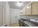 Functional laundry room with washer, dryer, storage cabinets, and exterior access at 3834 E Windsong Dr, Phoenix, AZ 85048