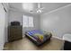 Comfortable bedroom offers a window for natural light, wood-look floors and a ceiling fan at 40893 W Bedford Dr, Maricopa, AZ 85138