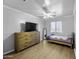 Cozy bedroom features wood-look floors, ceiling fan, dresser and a window with natural light at 40893 W Bedford Dr, Maricopa, AZ 85138