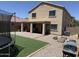 View of the backyard featuring artificial turf, a fire pit, a covered patio, and a partial view of a trampoline at 42775 W Jeremy St, Maricopa, AZ 85138