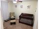 Cozy bedroom featuring a dark wood crib, comfortable chair, and soft lighting at 42775 W Jeremy St, Maricopa, AZ 85138