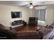 Inviting living area featuring a mounted TV, ceiling fan, and comfortable seating arrangements at 42775 W Jeremy St, Maricopa, AZ 85138