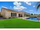 Landscaped backyard featuring a sparkling pool, lush lawn, and a covered patio for outdoor enjoyment at 43998 W Palo Abeto Dr, Maricopa, AZ 85138