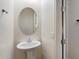 Bathroom with pedestal sink and oval mirror on a light wall at 43998 W Palo Abeto Dr, Maricopa, AZ 85138