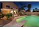 A private backyard featuring a pool, patio area, mature landscaping, and outdoor amenities at dusk at 44158 W Cypress Ln, Maricopa, AZ 85138