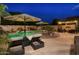 A beautiful backyard featuring a private pool, lounge chairs, and outdoor dining area at night at 44158 W Cypress Ln, Maricopa, AZ 85138