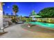 Relaxing backyard featuring a private pool, lounge chairs, and lush palm trees under the night sky at 44158 W Cypress Ln, Maricopa, AZ 85138
