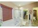 Bright bathroom features a soaking tub, glass shower, and walk-in closet with a neutral color palette at 44158 W Cypress Ln, Maricopa, AZ 85138