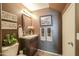 Cozy half bath featuring dark brown walls, decorative art, a white sink, and brown tile flooring, creating a warm ambiance at 44158 W Cypress Ln, Maricopa, AZ 85138