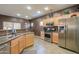 Well-lit kitchen with stainless steel appliances, wooden cabinetry, and a breakfast bar, perfect for meal preparation and casual dining at 44158 W Cypress Ln, Maricopa, AZ 85138