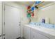 Bright laundry room featuring a modern washer and dryer, storage shelves, and an exterior door for easy access at 44158 W Cypress Ln, Maricopa, AZ 85138