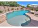 Beautiful backyard pool with built-in seating and rock features at 44158 W Cypress Ln, Maricopa, AZ 85138