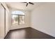 An empty room with dark wood floor, a ceiling fan, and a large window that lets in plenty of natural light at 7239 E Madero Ave, Mesa, AZ 85209