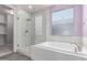 A bathroom with a glass shower and a soaking tub under a frosted window at 8010 W Atlantis Way, Phoenix, AZ 85043