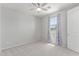 A simple bedroom with light gray walls, carpet, a ceiling fan, and a window with blue patterned curtains at 8010 W Atlantis Way, Phoenix, AZ 85043