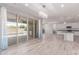 Open-concept living room with seamless access to a patio, tiled floors, modern lighting, and an adjacent kitchen at 8010 W Atlantis Way, Phoenix, AZ 85043