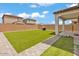 Expansive backyard with artificial turf, paver walkway, and covered patio, perfect for outdoor entertaining at 9444 W Roma Ave, Phoenix, AZ 85037