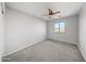 This bright bedroom boasts a ceiling fan, carpeted floors, and a large window overlooking the neighborhood at 9719 W Heber Rd, Tolleson, AZ 85353