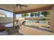 Covered patio with seating and views of the pool and waterfall feature at 9719 W Heber Rd, Tolleson, AZ 85353