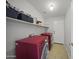 Well-lit laundry room with red washer and dryer units, shelving, and a storage closet at 9719 W Heber Rd, Tolleson, AZ 85353