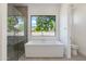 Modern bathroom with a sleek bathtub, glass enclosed shower, and bright window at 100 W Northern Ave # 12, Phoenix, AZ 85021