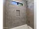 Close up of a shower with designer accent tiling, a shower niche, and a window view to the outdoors at 100 W Northern Ave # 12, Phoenix, AZ 85021