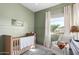 Charming Bedroom with sage green walls, wood crib, rocker and natural light at 10206 E Texas Ave, Mesa, AZ 85212