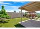 Landscaped backyard featuring artificial turf, a covered patio, a pergola, and a stone tile patio at 1049 N Monterey St, Gilbert, AZ 85233