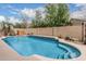 Beautiful pool with curved edges, surrounded by lush landscaping and a brick wall, creating a private oasis at 11611 N 149Th Ln, Surprise, AZ 85379
