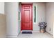 Inviting front entrance featuring a red door with sidelight windows and decorative potted plants at 13228 W Buckskin Trl, Peoria, AZ 85383