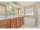 Bathroom with double sinks, drawers, soaking tub, walk-in shower, large mirror and neutral flooring at 15420 W Canterbury Dr, Surprise, AZ 85379