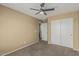 A bedroom featuring neutral walls, carpet, ceiling fan, and a double door closet at 15420 W Canterbury Dr, Surprise, AZ 85379