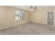 Bright, carpeted bedroom with a ceiling fan and a view of the neighborhood at 15420 W Canterbury Dr, Surprise, AZ 85379