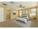 Bright main bedroom featuring a ceiling fan, ensuite bathroom, and warm, neutral decor at 15420 W Canterbury Dr, Surprise, AZ 85379