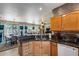 A close up shot of a kitchen sink with black granite countertops, wood cabinetry, and stainless steel appliances at 15976 W La Paloma Dr, Surprise, AZ 85374