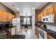 Bright kitchen with tile flooring, stainless steel appliances, wood cabinetry, and granite countertops at 15976 W La Paloma Dr, Surprise, AZ 85374