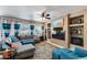 Comfortable living room featuring a large sectional, built-in shelving, ceiling fan, and large windows at 15976 W La Paloma Dr, Surprise, AZ 85374