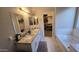 Bathroom featuring a dual sink vanity, granite countertops, and a soaking tub at 16046 W Hearn Rd, Surprise, AZ 85379